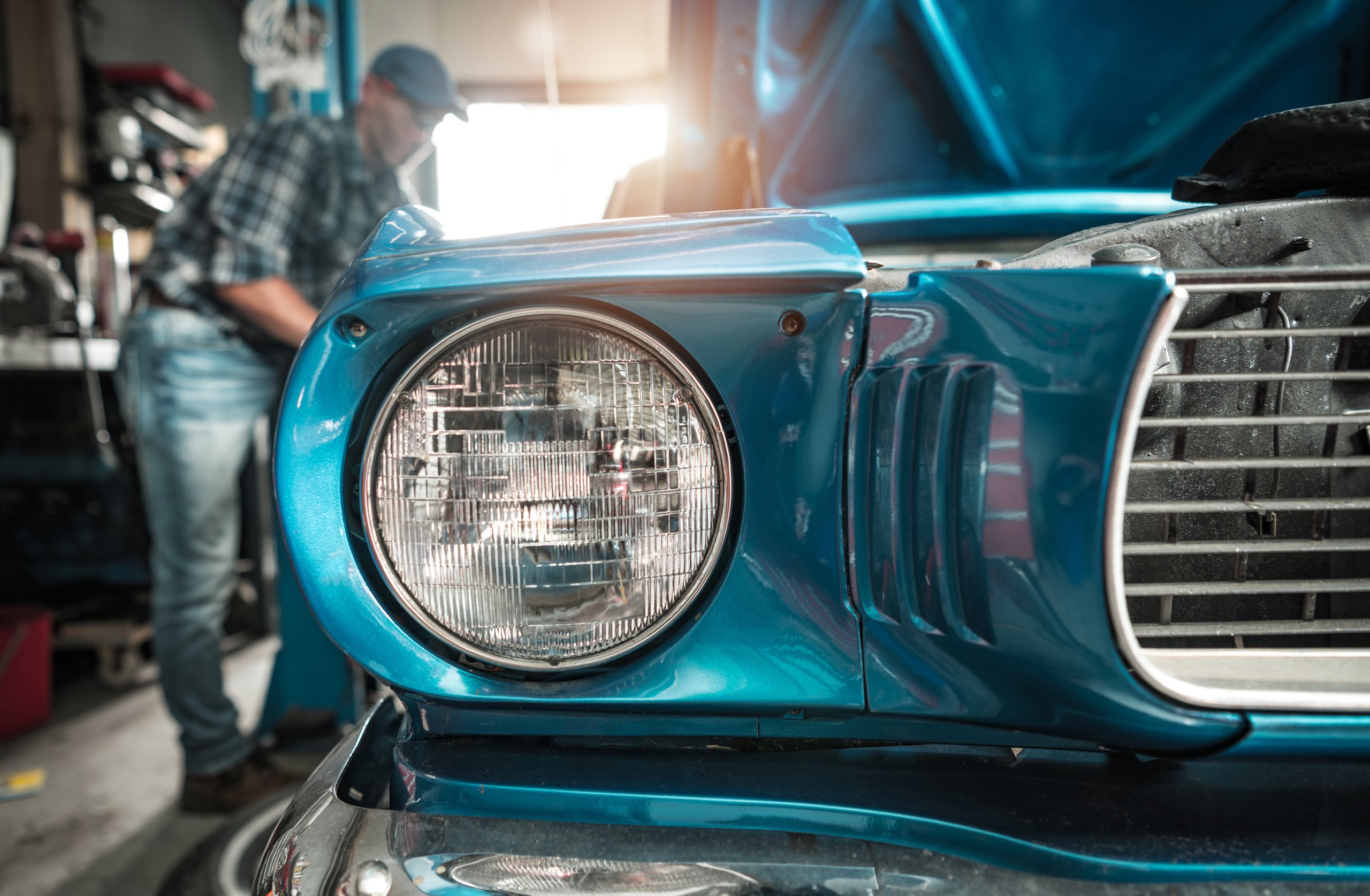 Restoration worker standing next to a fully restored classic vehicle